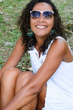 Çimlerin üzerinde oturmuş kameraya bakan siyah modelin portresi. Neşe kavramı, olgunluk ve siyah farkındalık. Salvador, Bahia, Brezilya.