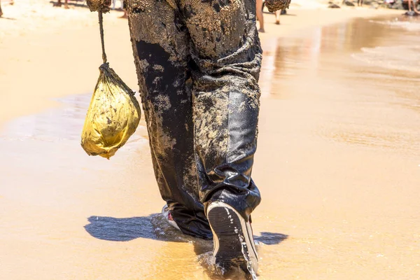 Man covered in oil on the beach at Porto da Barra in Salvador, Bahia, in protest of oil spilled by a ship on the beaches of Brazil.