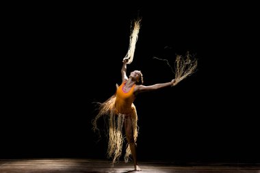 Çağdaş dansçı siyah arka plan ve saman aksesuarlarıyla tiyatroda dans ediyor. Salvador Bahia Brezilya.