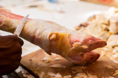 Domuz ayağı kasap bıçağıyla temizleniyor. Feira de Sao Joaquim, Salvador, Bahia, Brezilya.