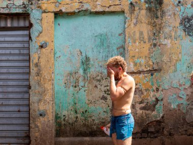 Adam protesto gösterisi yapmaya hazırlanıyor. Üstsüz, çekiç, çivi ve balık kullanıyor. Salvador Bahia Brezilya.