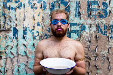 Adam Salvador 'daki Sao Joaquim fuarında protesto gösterisi yapıyor. Üstsüz, elinde beyaz bir su havuzu var ve dalış gözlüğü takıyor. Salvador Bahia Brezilya.