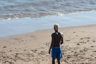 Genç manken, kumsalda güçlü yaz güneşi altında futbol oynuyor. Salvador Bahia Brezilya.