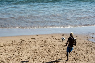Genç manken, kumsalda güçlü yaz güneşi altında futbol oynuyor. Salvador Bahia Brezilya.