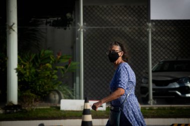 Salvador, Bahia, Brezilya - 21 Mayıs 2021: Yüz maskesi takan ve Salvador, Bahia, Brezilya sokaklarında yürüyen kadın.