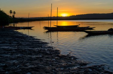 Brezilya 'nın Bahia eyaletindeki Paraguacu nehrine kanoların günbatımında siluet yanaştı..