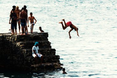 Salvador, Bahia, Brezilya - 08 Ocak 2019: Porto da Barra 'daki Santa Maria Kalesi' nden denize atlayan gençler.