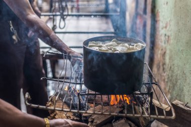 Erkekler, Sao Joaquim pazarında odun ateşiyle birlikte demir bir tencerede cassava pişiriyorlar. Salvador Bahia Brezilya.