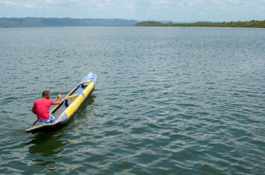 Cachoeira, Bahia, Brezilya - 29 Kasım 2014: Brezilya 'nın Bahia eyaletinde yer alan büyük Paraguacu nehrinde mavi ve sarı renkli kanosunu yüzdüren balıkçı.