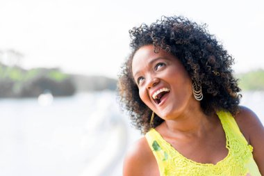 Siyah kadın fotoğraf için poz veriyor. Sarı giyiniyor, gülümsüyor ve kameraya bakıyor. Salvador, Bahia, Brezilya.