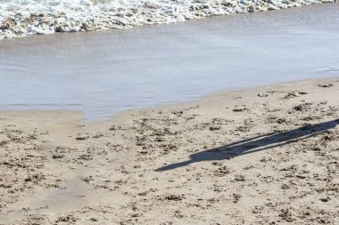 Güçlü, güneşli bir günde, Ondina sahilindeki bir insanın gölgesi. Salvador Bahia Brezilya.