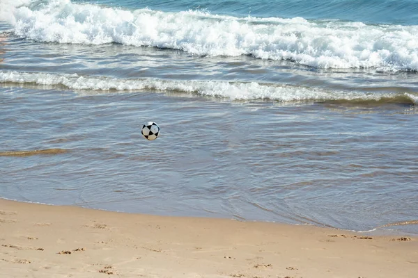 Sand soccer ball flying in the sands of the beach of Ondina. Salvador, Bahia, Brazil.