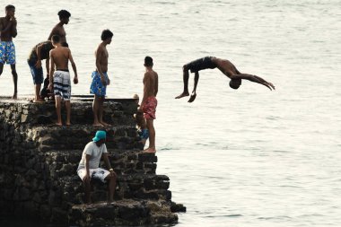 Salvador, Bahia, Brezilya - 08 Ocak 2019: Porto da Barra 'daki Santa Maria Kalesi' nden denize atlayan gençler.