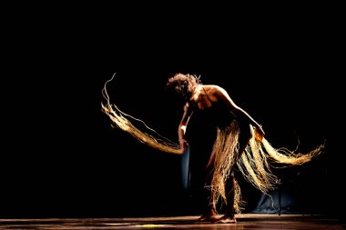 Çağdaş dansçı siyah arka plan ve saman aksesuarlarıyla tiyatroda dans ediyor. Salvador Bahia Brezilya.