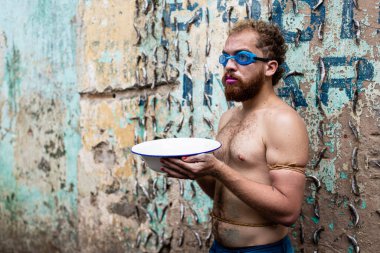 Adam Salvador 'daki Sao Joaquim fuarında protesto gösterisi yapıyor. Üstsüz, elinde beyaz bir su havuzu var ve dalış gözlüğü takıyor. Salvador Bahia Brezilya.