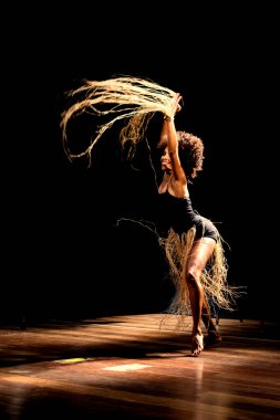 Çağdaş dansçı siyah arka plan ve saman aksesuarlarıyla tiyatroda dans ediyor. Salvador Bahia Brezilya.
