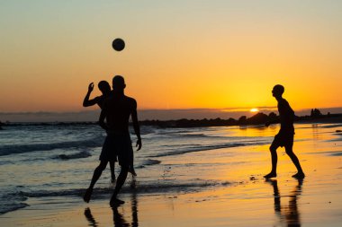 Salvador, Bahia, Brezilya - 08 Ocak 2020: Salvador, Bahia, Brezilya 'da gün batımında Ondina plajında kum futbolu oynayan gençler.    