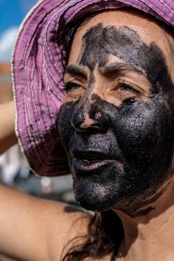 Yüzü siyah renge boyanmış pembe şapkalı bir kadın. Onun yeşil gözleri var. Acupe, Bahia, Brezilya.