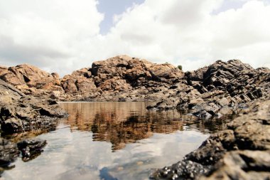 Farol da Barra sahilinde kayalar, deniz, gökyüzü ve bulutlar. Salvador Bahia Brezilya.