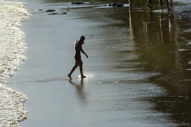 Salvador, Bahia, Brezilya - Janeiro 08, 2020: Adam banyo yaptıktan sonra yavaşça Ondina sahilinden geliyor. Salvador Bahia Brezilya.