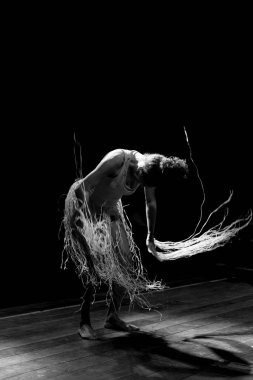 Çağdaş dansçı siyah arka plan ve saman aksesuarlarıyla tiyatroda dans ediyor. Salvador Bahia Brezilya.