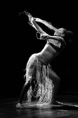 Çağdaş dansçı siyah arka plan ve saman aksesuarlarıyla tiyatroda dans ediyor. Salvador Bahia Brezilya.