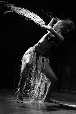 Çağdaş dansçı siyah arka plan ve saman aksesuarlarıyla tiyatroda dans ediyor. Salvador Bahia Brezilya.