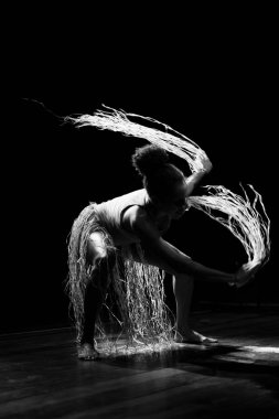 Çağdaş dansçı siyah arka plan ve saman aksesuarlarıyla tiyatroda dans ediyor. Salvador Bahia Brezilya.