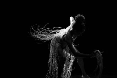 Çağdaş dansçı siyah arka plan ve saman aksesuarlarıyla tiyatroda dans ediyor. Salvador Bahia Brezilya.