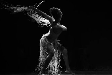Çağdaş dansçı siyah arka plan ve saman aksesuarlarıyla tiyatroda dans ediyor. Salvador Bahia Brezilya.