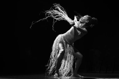 Çağdaş dansçı siyah arka plan ve saman aksesuarlarıyla tiyatroda dans ediyor. Salvador Bahia Brezilya.