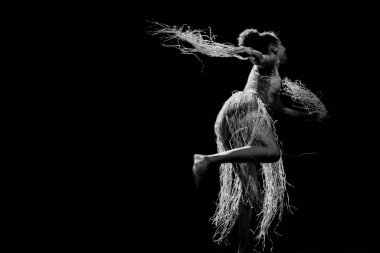 Çağdaş dansçı siyah arka plan ve saman aksesuarlarıyla tiyatroda dans ediyor. Salvador Bahia Brezilya.