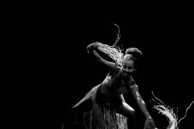 Çağdaş dansçı siyah arka plan ve saman aksesuarlarıyla tiyatroda dans ediyor. Salvador Bahia Brezilya.