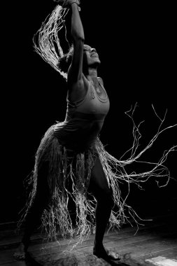 Çağdaş dansçı siyah arka plan ve saman aksesuarlarıyla tiyatroda dans ediyor. Salvador Bahia Brezilya.