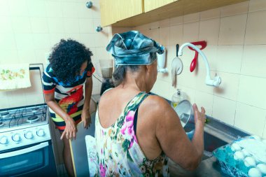 Anne ve kızı mutfakta yemek yapıyor. Salvador, Bahia, Brezilya.