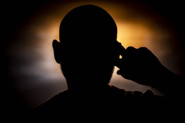 Turuncu arka planda bir adamın kafasının yakın plan silueti. Salvador, Bahia, Brezilya.