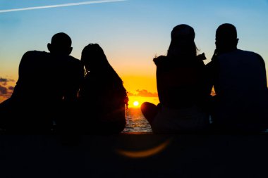 Salvador, Bahia, Brazil - August 15, 2021: Silhouette of four people enjoying the sunset at Ponta do Humatia in Salvador, Bahia, Brazil.