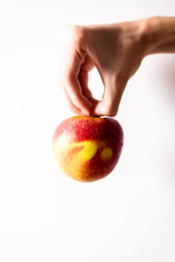 Beyaz arka planda elmayı tutan bir el. Salvador, Bahia, Brezilya.