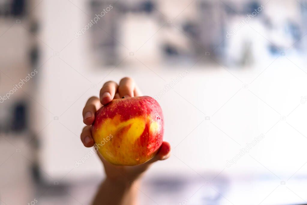 A hand holding an apple against white background. Salvador, Bahia, Brazil.