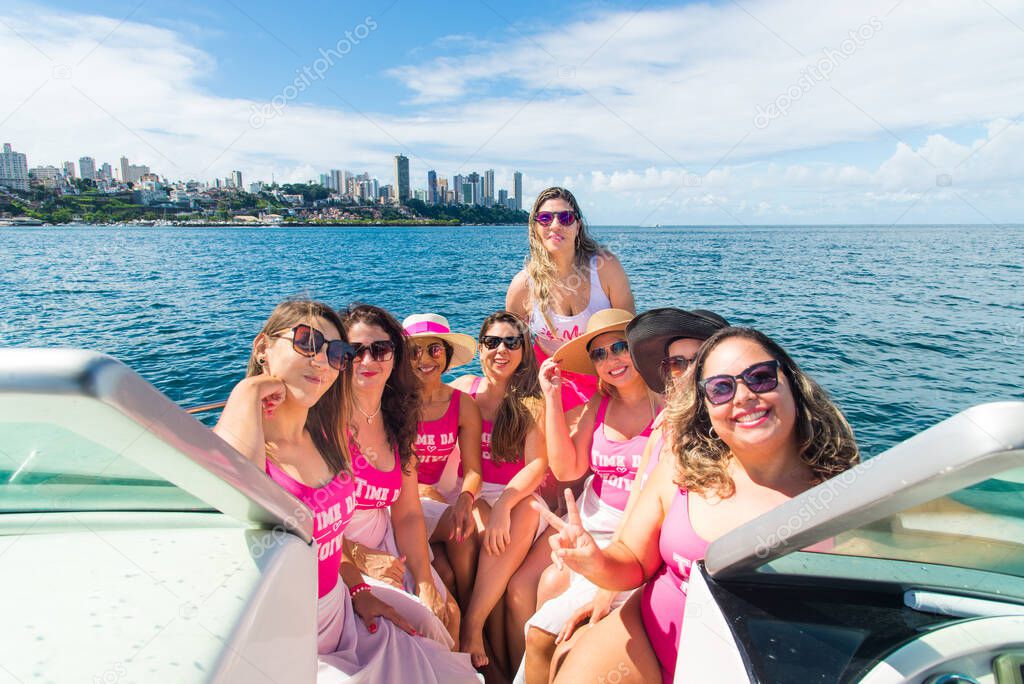 Women in bikini sitting on a boat wearing pink outfit. Salvador, Bahia, Brazil.