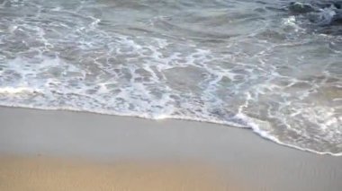 Kumsal dalgaları kum ve kayalara çarpıyor..