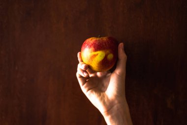 Karanlık bir arka planda elmayı tutan bir el. Salvador, Bahia, Brezilya.