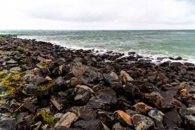 Dalgalı deniz sahildeki kayalara çarpıyor. Rio Vermelho, Salvador, Bahia, Brezilya.