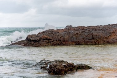 Dalgalı deniz sahildeki kayalara çarpıyor. Rio Vermelho, Salvador, Bahia, Brezilya.