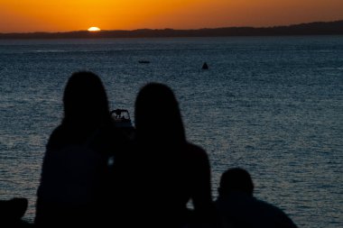 Gün batımına karşı bir grup insan silueti. Salvador, Bahia, Brezilya.