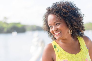 Siyah kadın fotoğraf için poz veriyor. Sarı giyiniyor, gülümsüyor ve kameraya bakıyor. Salvador, Bahia, Brezilya.