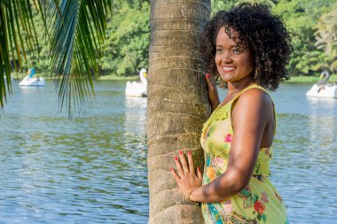 Siyah kadın fotoğraf için poz veriyor. Sarı giyiniyor, gülümsüyor ve kameraya bakıyor. Salvador, Bahia, Brezilya.