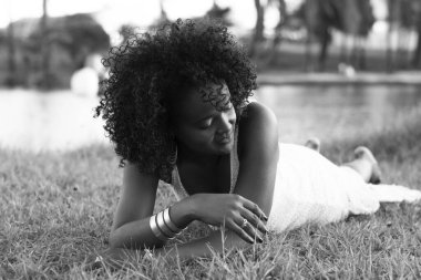 Beyaz elbiseli güzel bir manken gülümsüyor ve kameraya bakıyor. Arka planda, ağaçlar, bitkiler, çiçekler ve manzaradaki nehir. Salvador Bahia Brezilya.