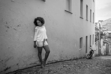 Beyaz elbiseli manken gülümsüyor, kameraya bakıyor ve poz veriyor. Arka planda, antik mimarisi ile Pelourinho 'nun tarihi merkezi. Neşe, aidiyet ve olgunluk kavramı. Salvador Bahia Brezilya.