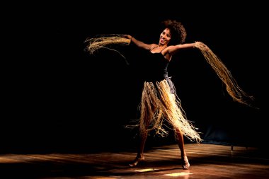 Çağdaş dansçı siyah arka plan ve saman aksesuarlarıyla tiyatroda dans ediyor. Salvador Bahia Brezilya.